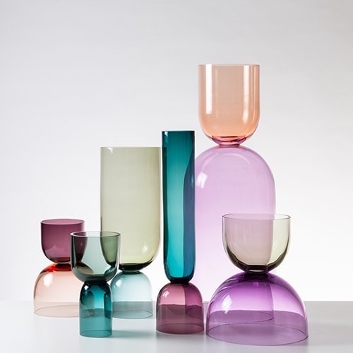 Minimalist glasses with two symmetrical faces of various colors and sizes on a white background.