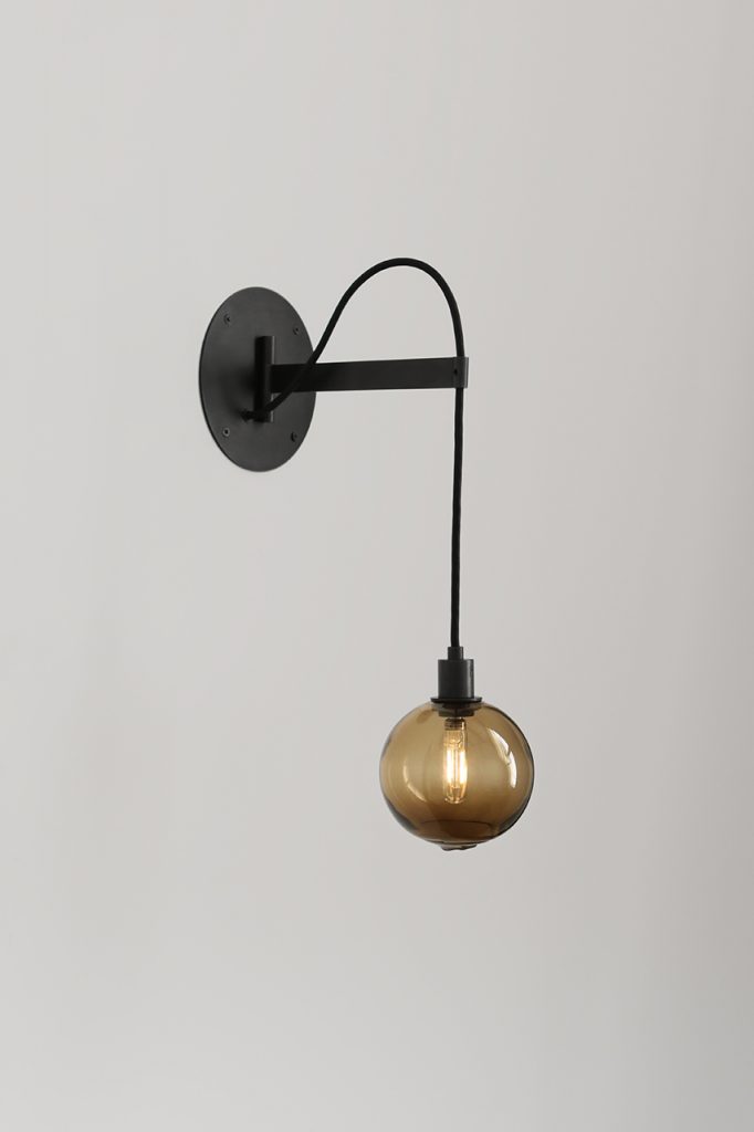 gold sphere lamp hanging on the wall with black base.