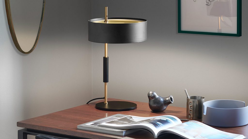 small table lamp made up of two metal and aluminum discs in black with gold finishes in a room
