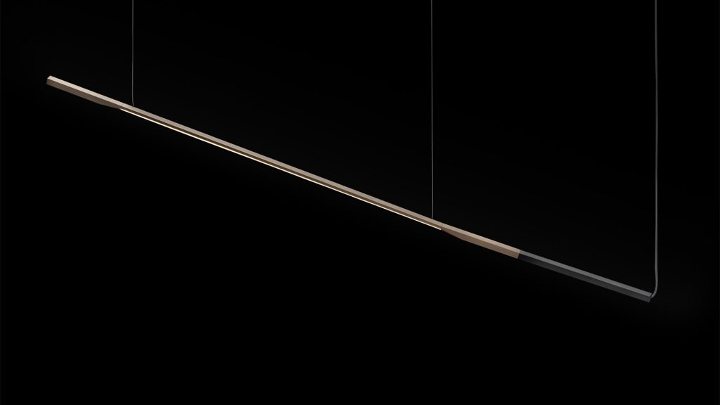 hanging lamp in the shape of a straight line made of aluminum in a gold and black tone on a black background
