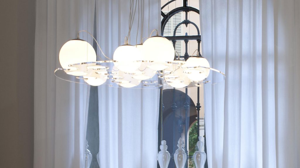 lamp made of transparent methacrylate with holes in its body where the luminous white spheres fall