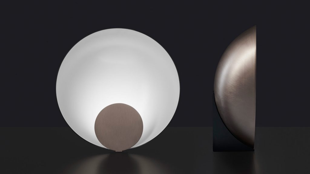 semicircular table lamp made of metal in a white tone with brown finishes on its sides