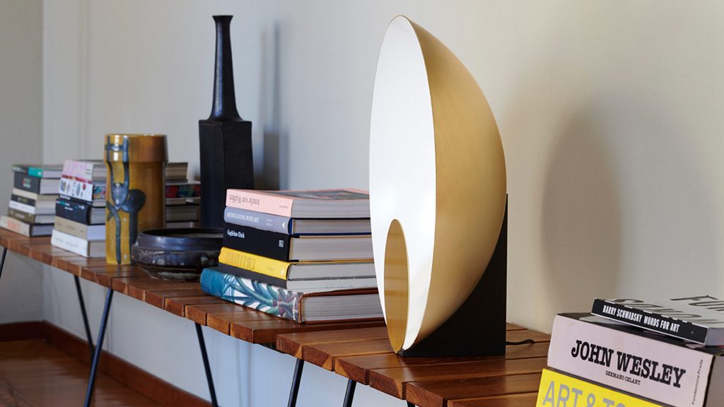 Lamp in the shape of a semicircle on a white metal base with golden finishes on its front disc
