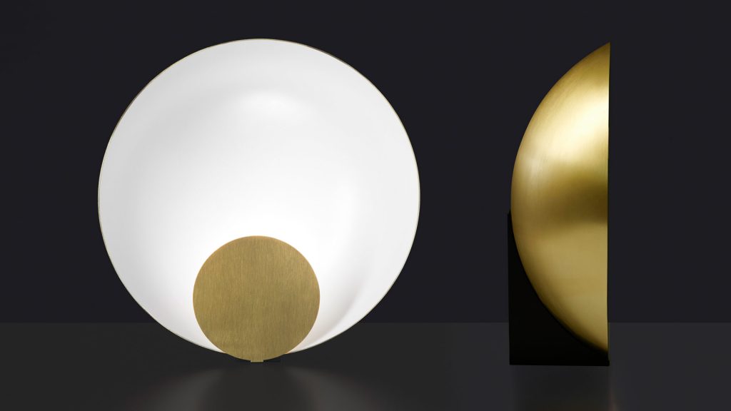 semicircular table lamp made of metal in a white tone with gold finishes on its sides