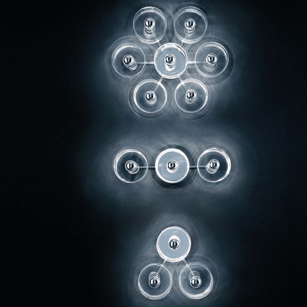 ceiling lamp made of clear glass and metal cylinders forming a flower on a black background