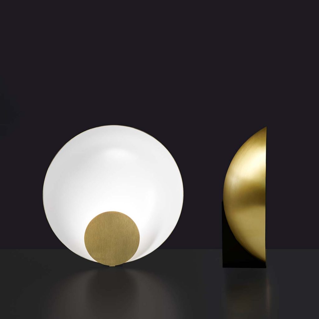 semicircular table lamp made of metal in a white tone with gold finishes on its sides