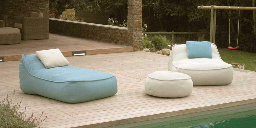 line of poufs made of fabric and polyretan foam in shades of gray and blue in an exterior
