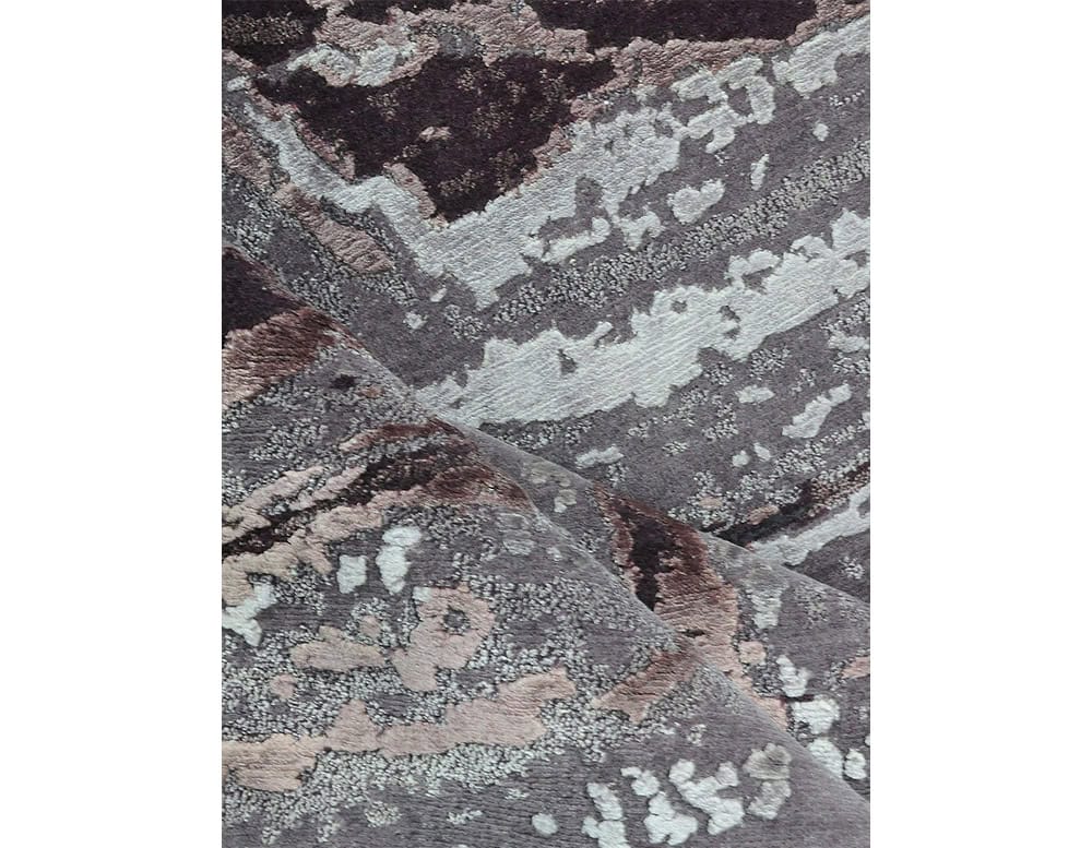 Acquasanta Rug features layered textures and abstract patterns in soft mauve, gray, and ivory tones. Its organic design evokes natural stone formations, adding depth and elegance to any interior setting.