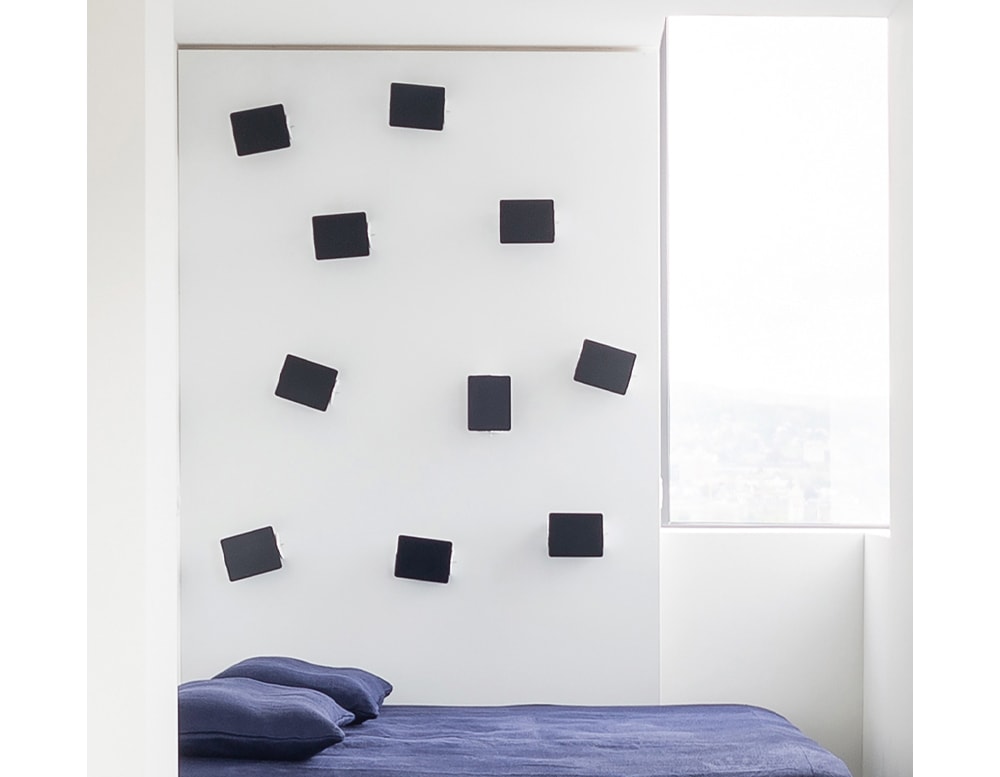 line of small gray illuminated aluminum diffusers on a wall