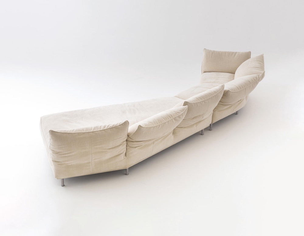 Modifiable sofa made of soft light beige fabric with metal base in a white background