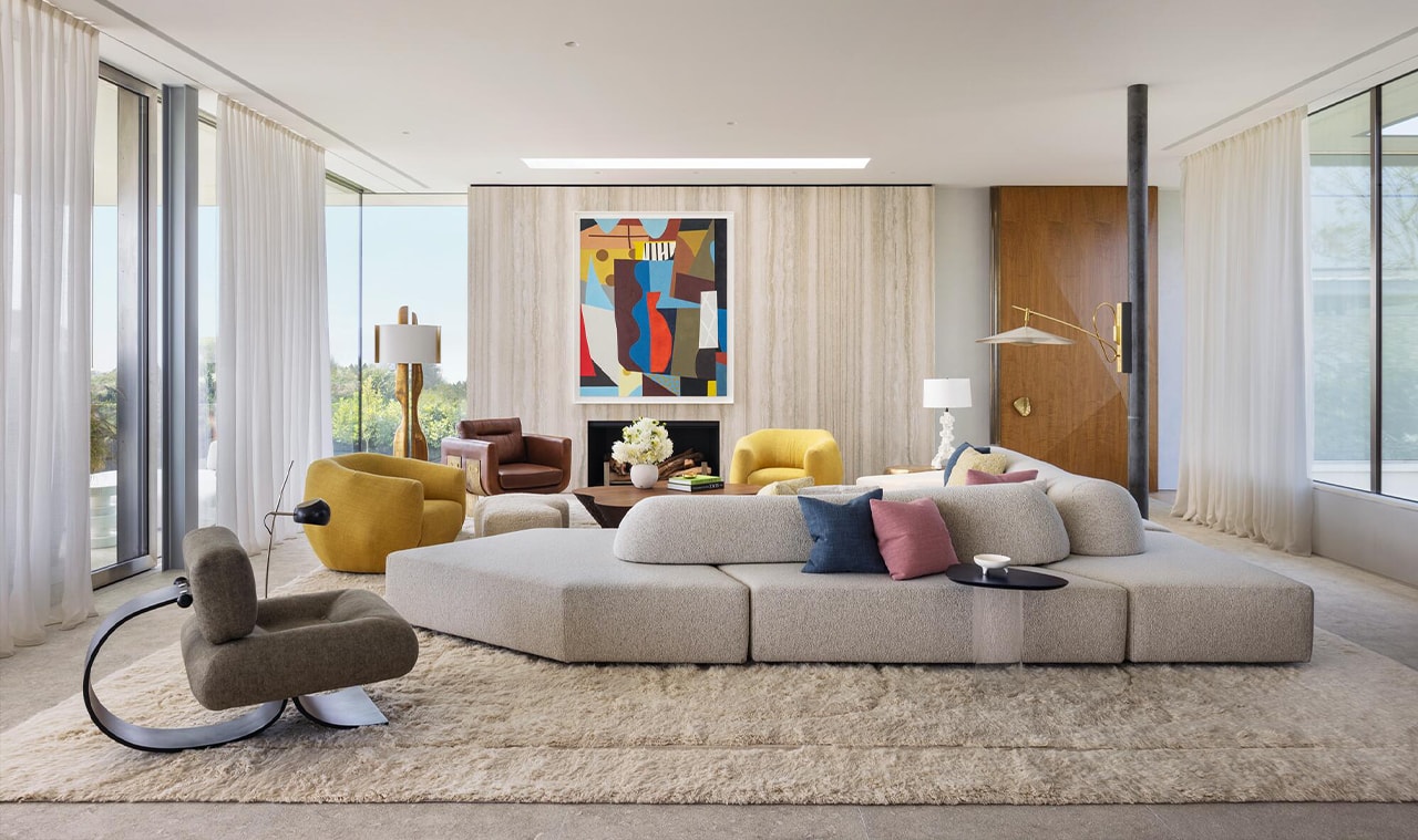 A modern living room with a modular sectional sofa, colorful accent chairs, and a bold abstract painting on the wall