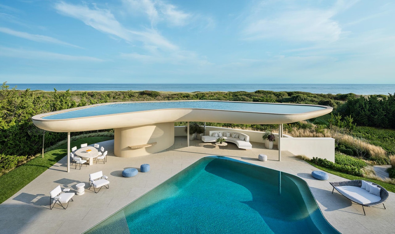 A stunning modern villa with a curved infinity pool overlooking the ocean, featuring sleek architecture and outdoor lounge areas