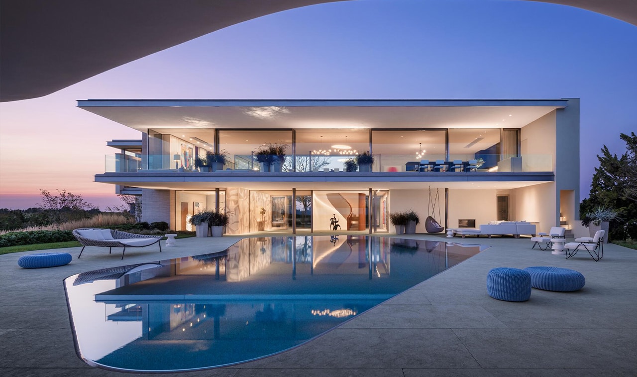A luxurious modern villa with an expansive pool, open-concept design, and ambient lighting at dusk