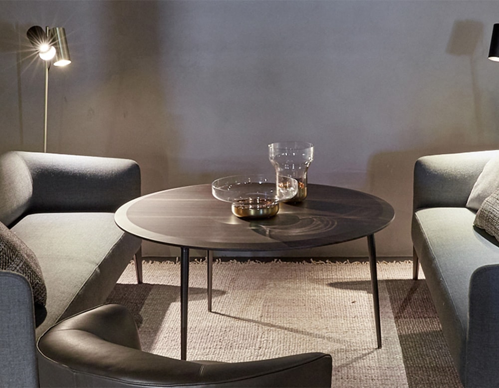 The Belsize Coffee Table features a sleek round design with a refined wood finish and minimalist metal legs, offering timeless elegance