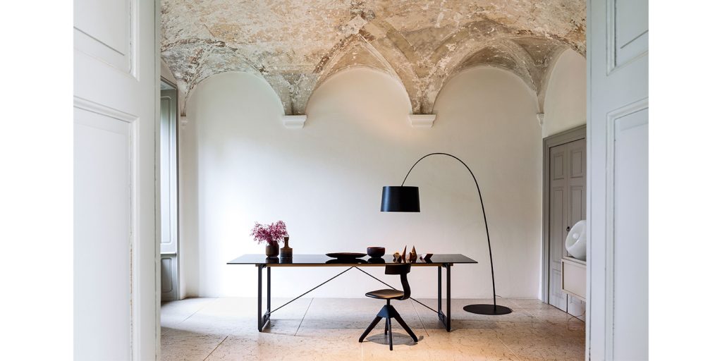 desk with aluminum or metal legs and square glossy black glass top in in a room