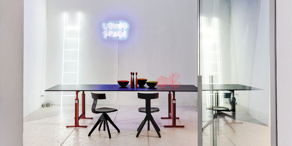 large square-shaped side table with metal base and glossy black thick glass top in a living room