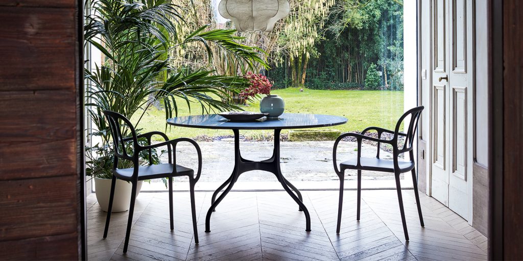stackable dining room chairs made of aluminum with black openings in the back in a dining room