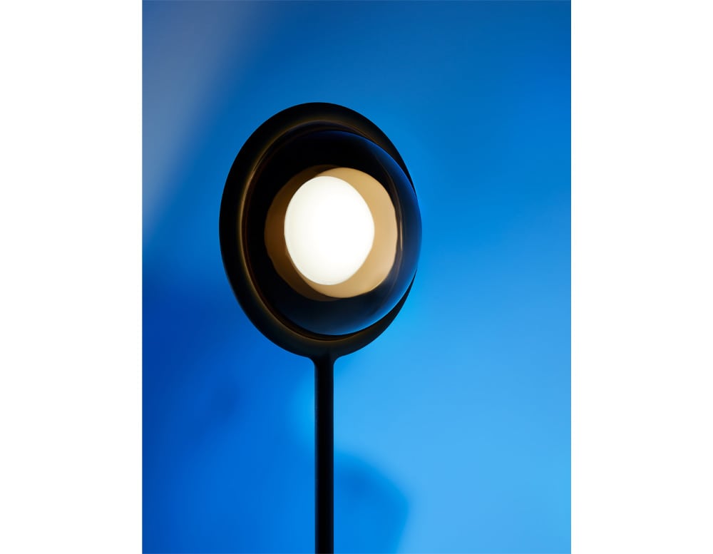 floor lamp with LED lighting in the shape of a sphere in a black and gold tone in a blue background