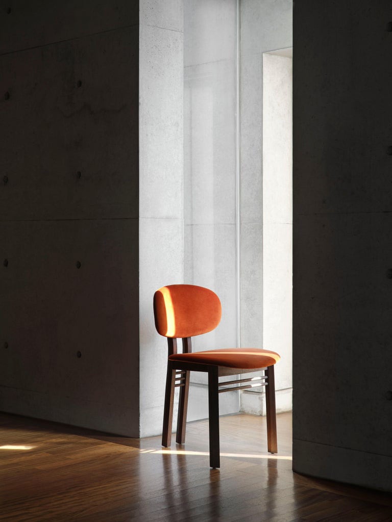 chair upholstered with fabric and shiny finishes in orange tone with ash wood base in a dark brown tone