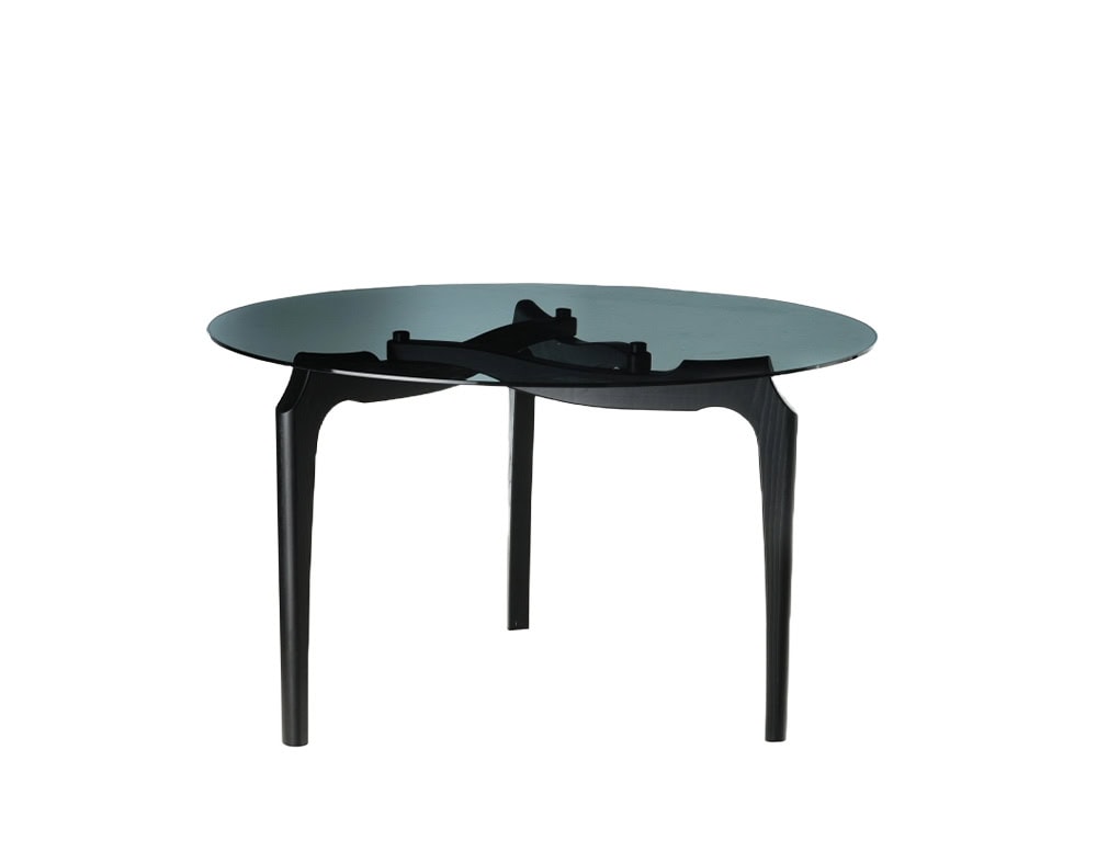 BD Carlina Round Dining Table features a smoked glass top resting on an elegant black wood frame with sculpted legs. Its refined silhouette highlights craftsmanship and balance, isolated against a clean white background.