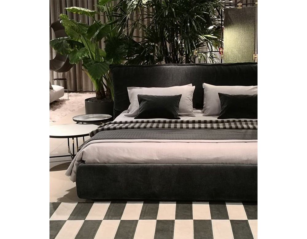 bed with a high cushion backrest and wooden base upholstered all in black fabric in a room