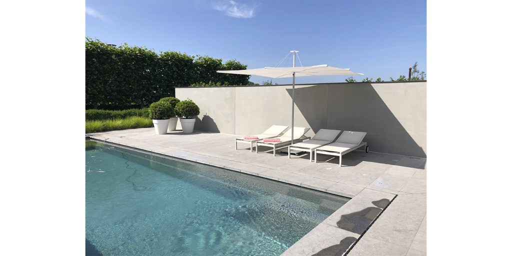 A serene poolside setting with the Infinia Umbrosa shade providing sleek, modern coverage over two sun loungers for a stylish outdoor relaxation space