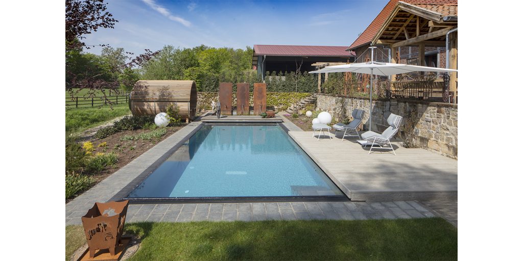A modern backyard pool area featuring the Infinia Umbrosa shade, blending sleek design with natural elements for a stylish and relaxing outdoor retreat