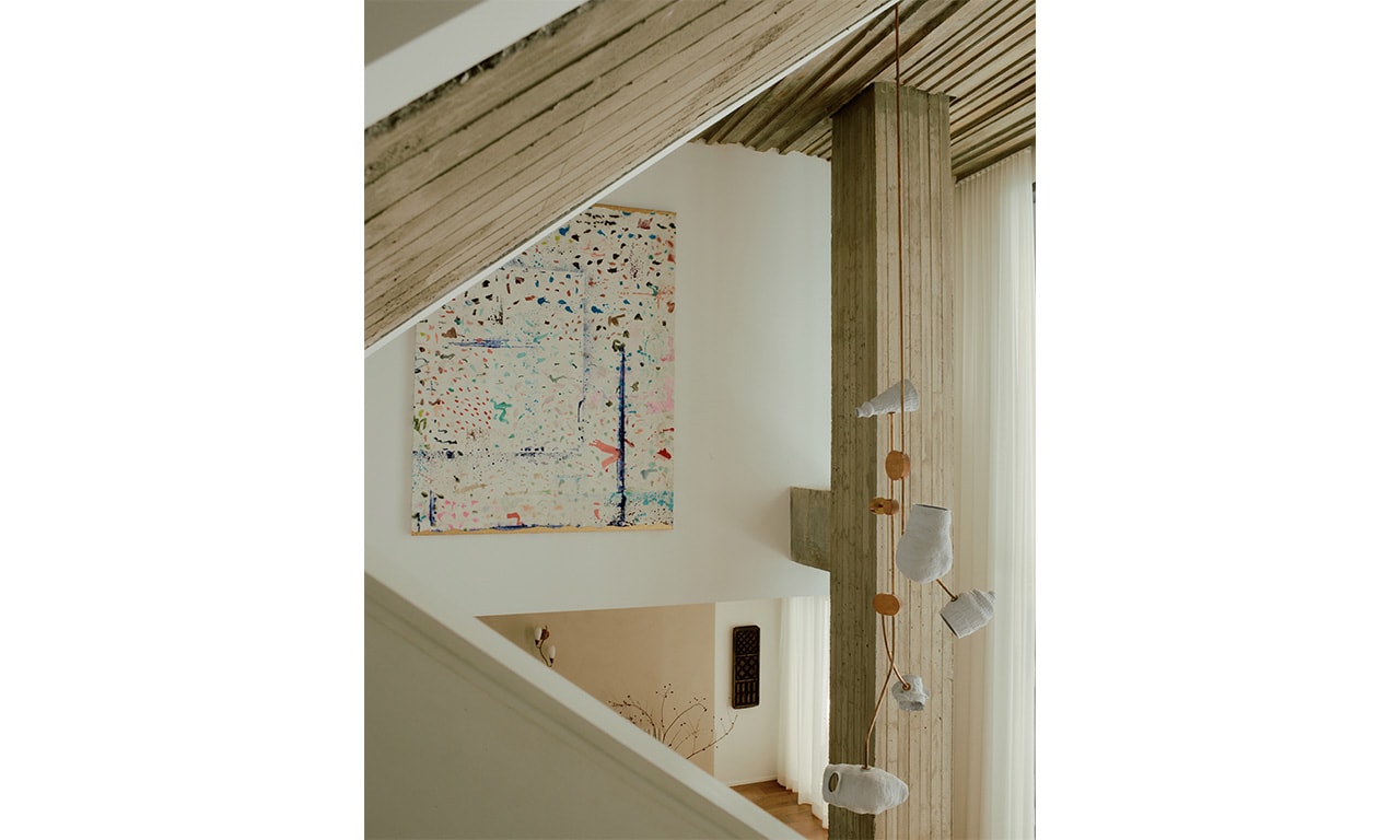 A contemporary staircase featuring wooden slats and a sculptural handrail, complemented by an abstract artwork on the wall for a modern aesthetic