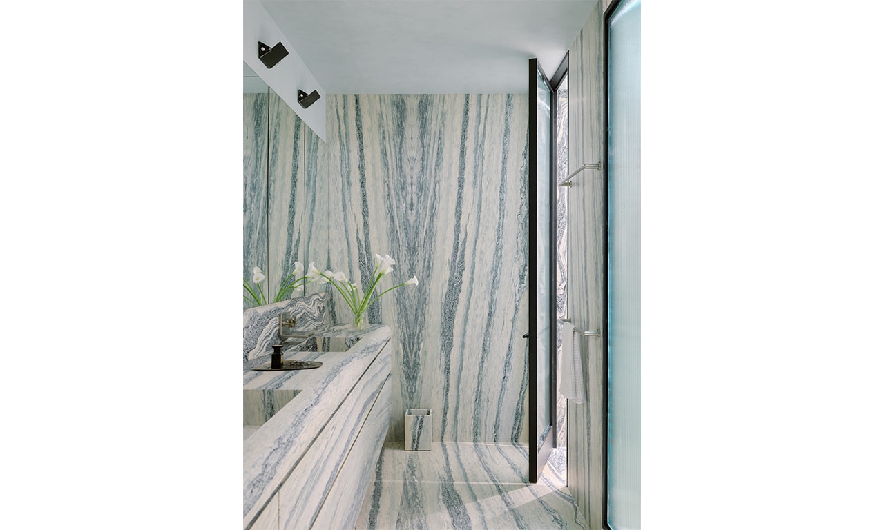 A stunning modern bathroom showcasing floor-to-ceiling marble with striking veining, seamlessly blending luxury and contemporary design