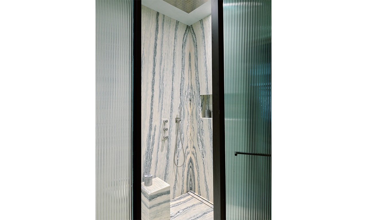 A luxurious bathroom featuring a sleek glass-enclosed shower with dramatic marble walls, exuding elegance and sophistication