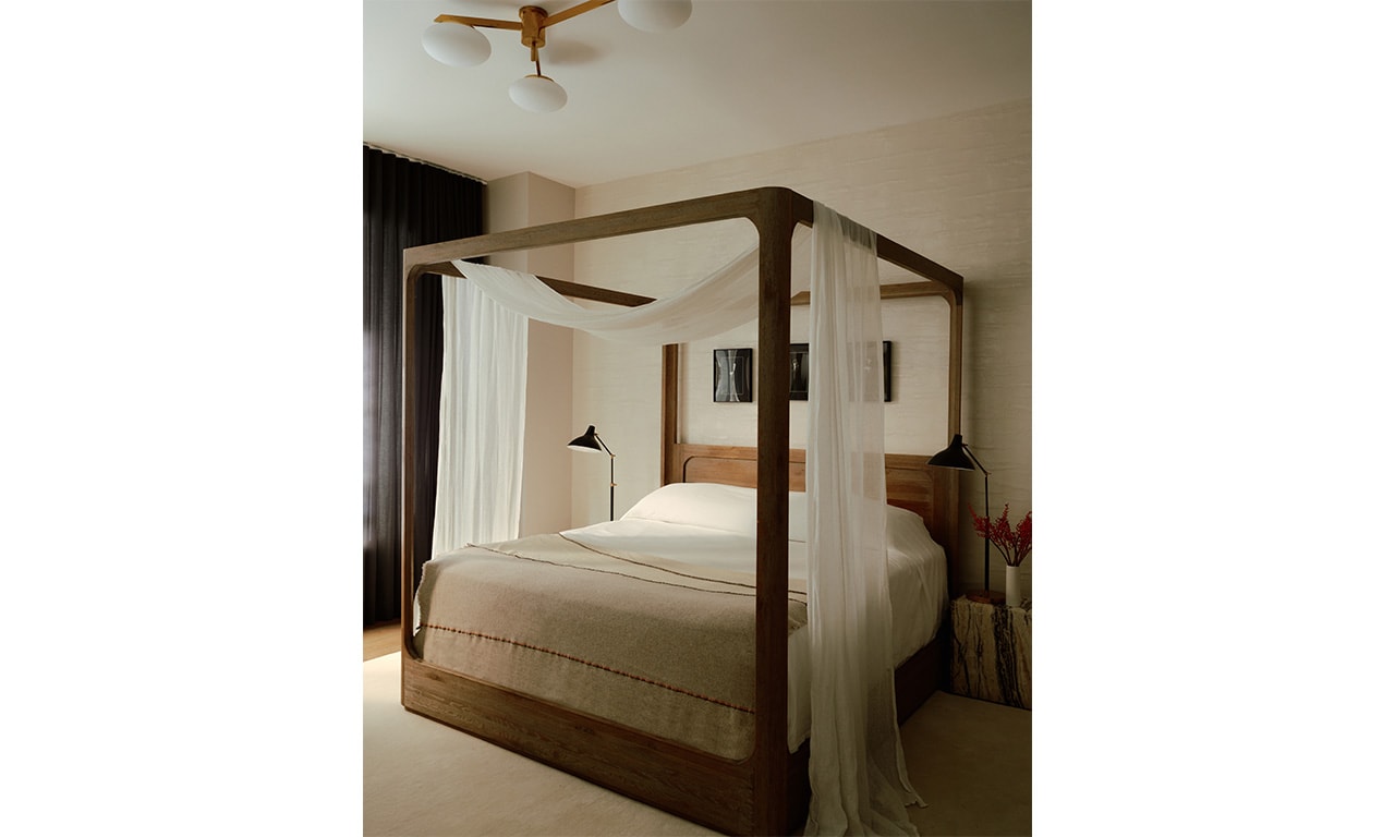A cozy bedroom featuring a wooden four-poster bed with sheer drapes, warm neutral tones, and soft lighting for a serene retreat