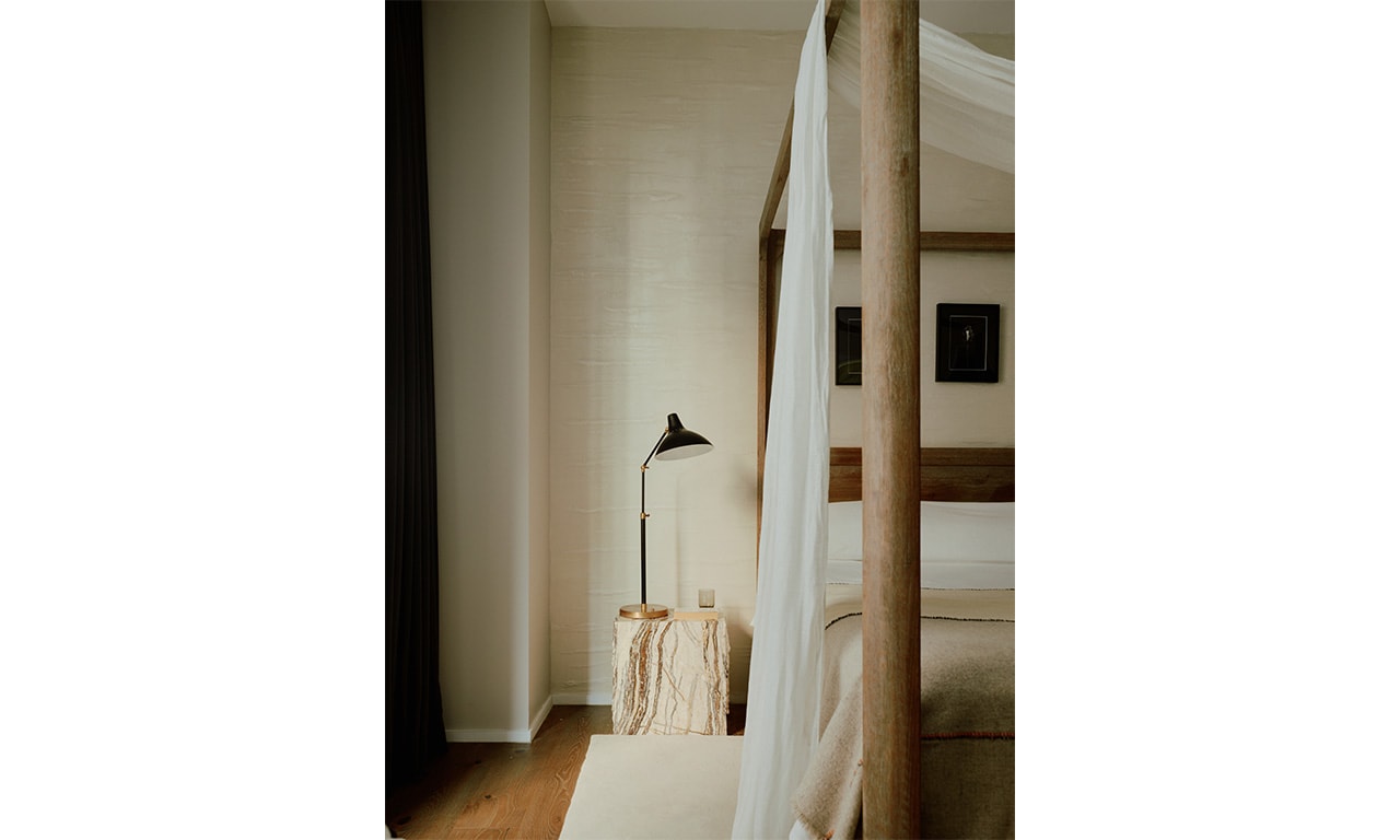 A serene bedroom with a minimalist four-poster bed, soft drapery, and warm neutral tones, creating a tranquil and inviting atmosphere