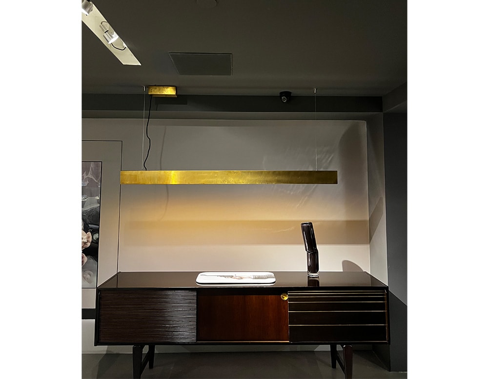 LED suspension lamp made with a golden antiqued satin brass structure in a room