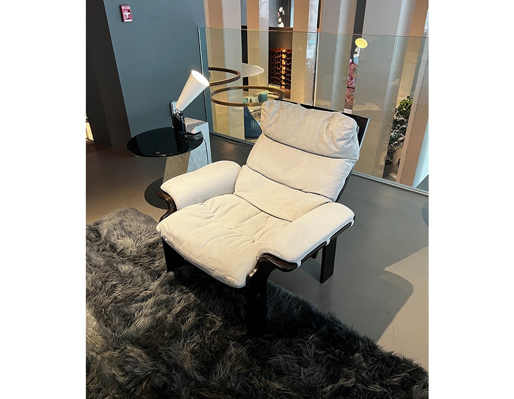 Side view of a dark brown wooden armchair finished in ice gray suede