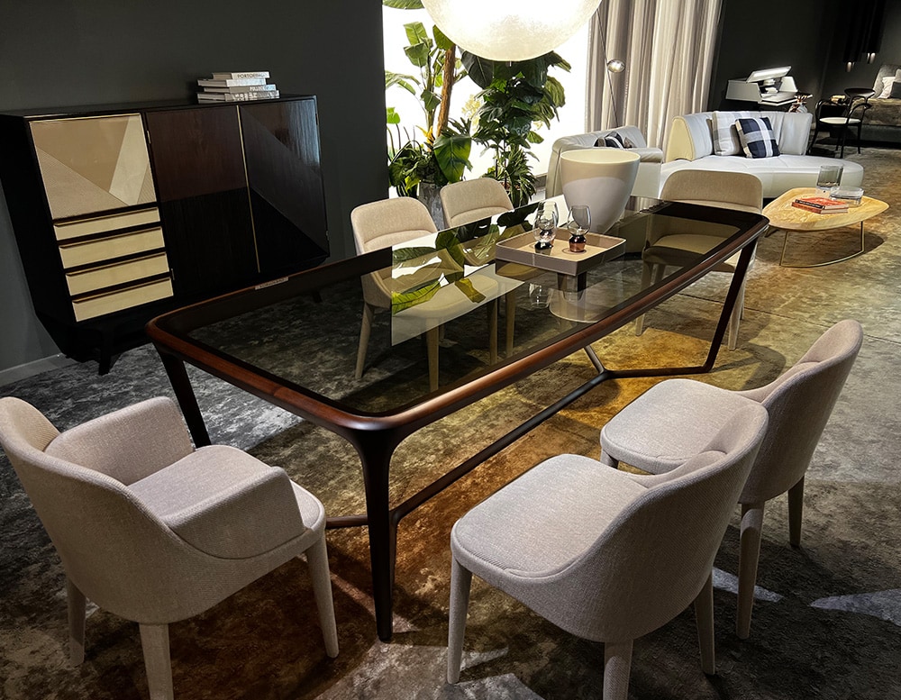 Side view of a dining table with a central cross-shaped wooden base sash, ties together the parts and supports the top made in glass color bronzed