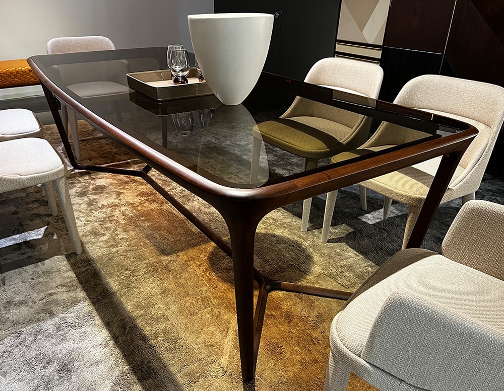 Detail view of a dining table with a central cross-shaped wooden base sash, ties together the parts and supports the top made in glass color bronzed