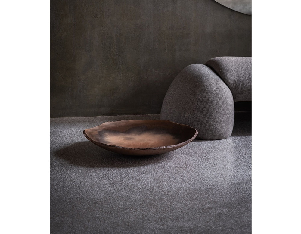 glass bowl of a particular brown color that is achieved by exposing the bowl to leaves and wood.
