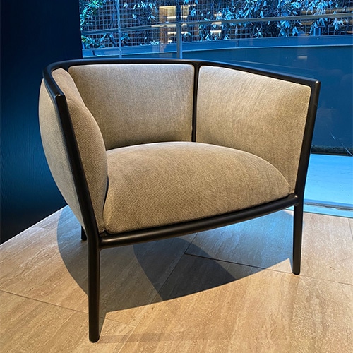 The Margou Armchair exudes elegance with its curved silhouette, luxurious upholstery, and refined wooden frame, offering both style and comfort