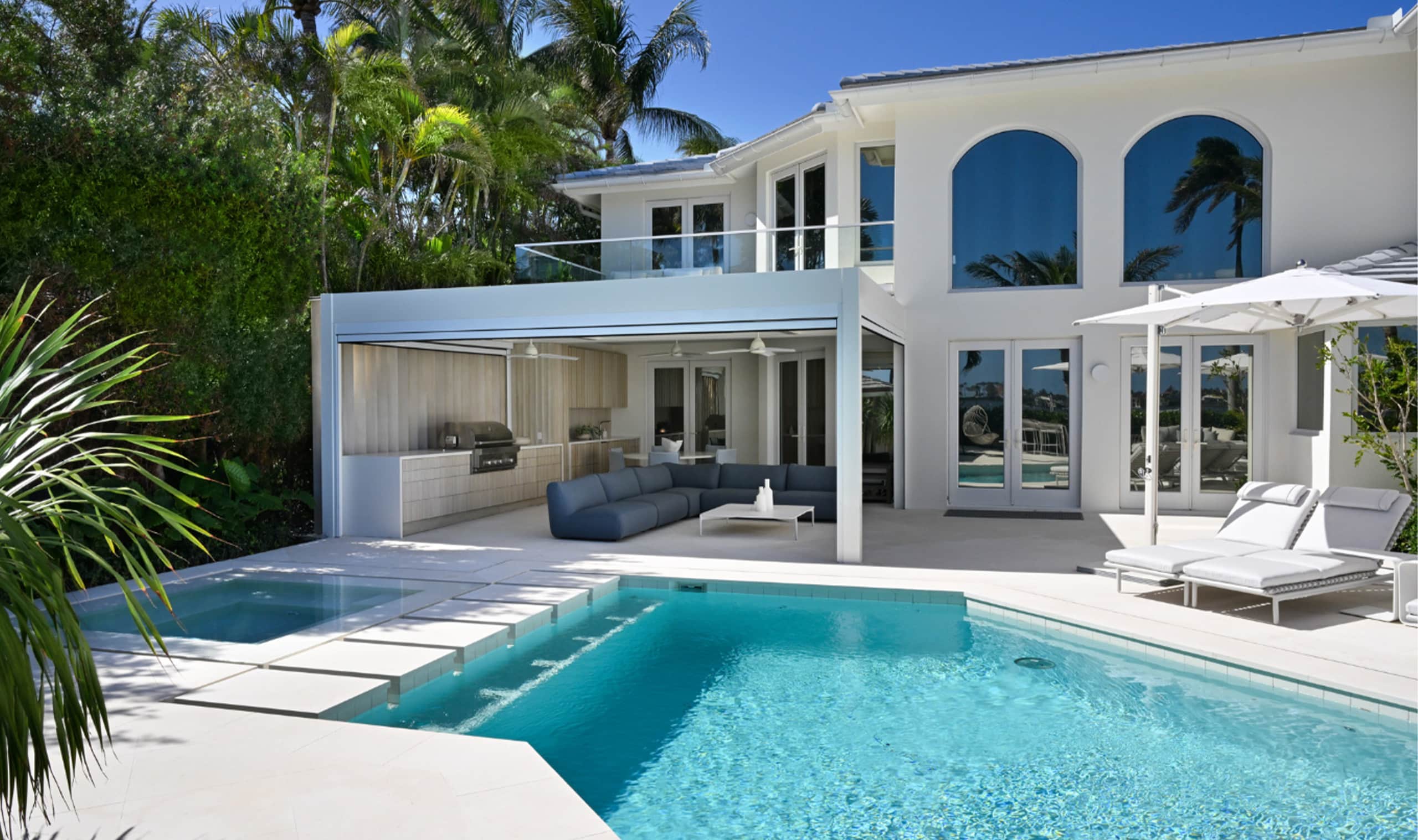 A luxurious modern villa with a sleek outdoor lounge, a sparkling pool, and lush greenery creating a private tropical oasis