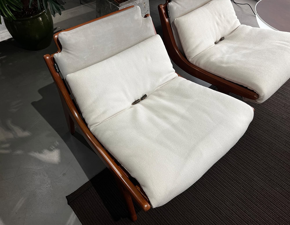 A close-up of the 10th Lerici Armchair showcasing its sleek wooden frame plush light-colored cushions and ergonomic design for outdoor relaxation