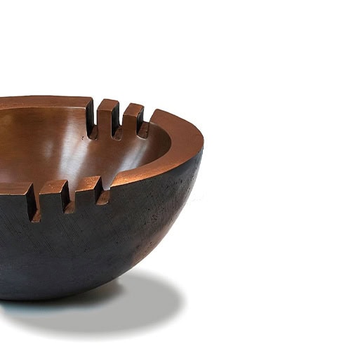Sculptural bronze bowl with a bold geometric cutout design. Its rich patina and striking form make it both functional and artistic, ideal as a centerpiece or decorative accent in refined interiors.