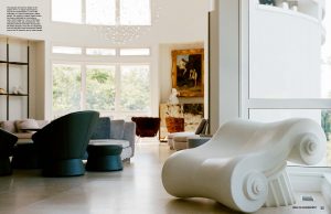 A modern minimalist living space with curved furniture large windows natural light and a mix of neutral and dark tones
