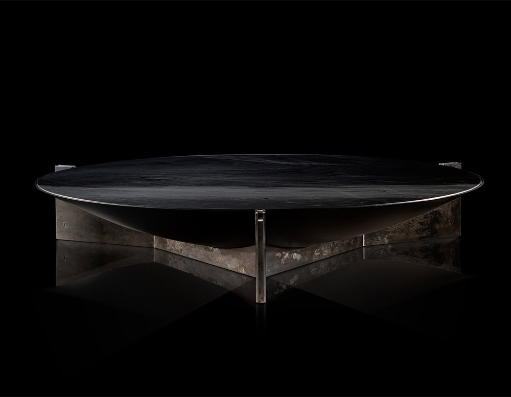 Hen Muse Coffee Table features a circular black marble top with deep gray veining, paired with a sculptural base in silvery and smoky brown tones, blending refined materials with bold geometric tension.