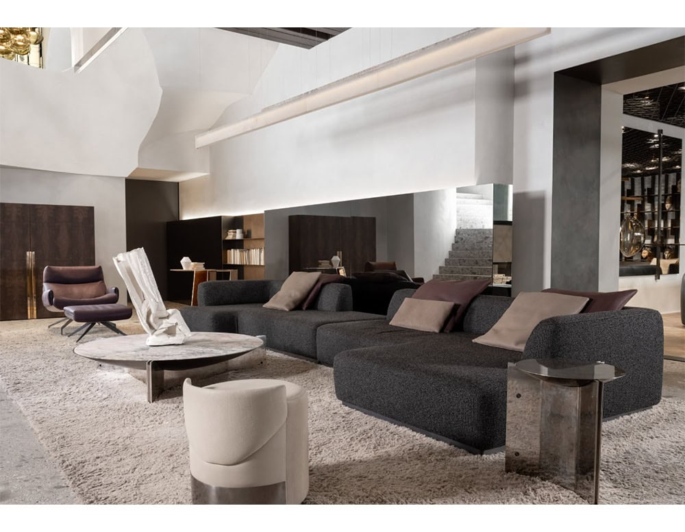 The Muse Coffee Table features a marbled white and gray stone top with a metallic base. It complements the dark charcoal modular sofa, neutral pillows, and the plush beige rug grounding the modern, open-concept space.