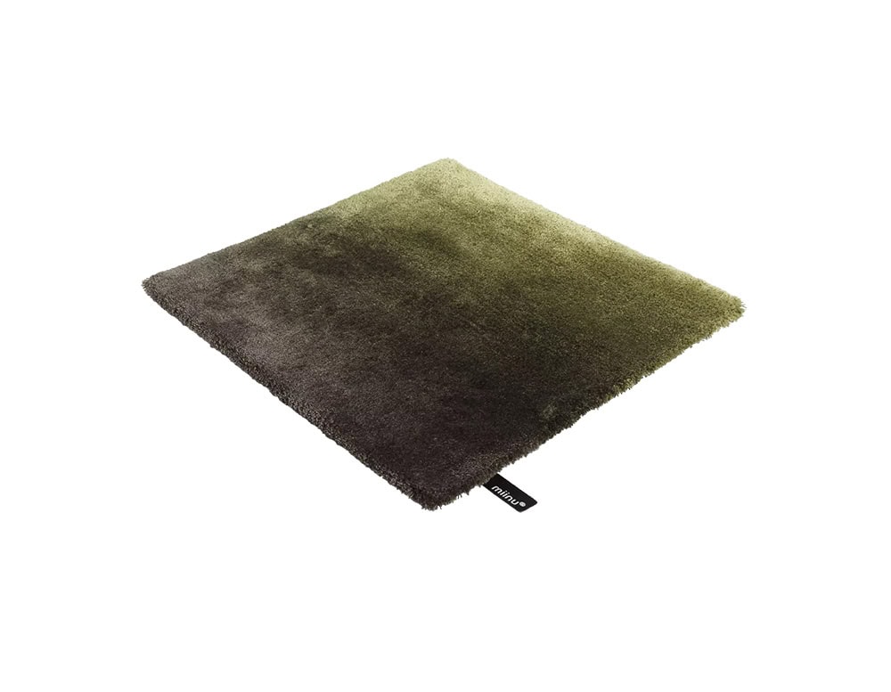 DeViant Rug features a plush gradient in earthy tones shifting from deep charcoal to olive green. Its soft texture and rich color palette make it a grounding element in contemporary interior compositions.