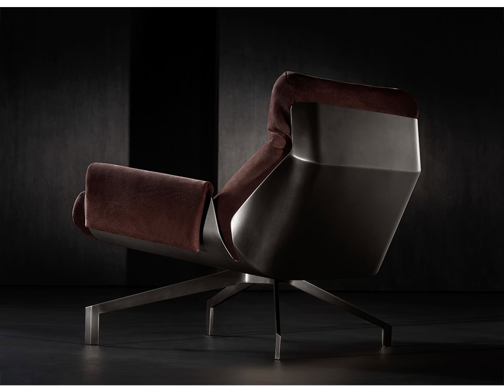 The Hen Club 57 Armchair is captured from the back, showcasing its sculpted metal shell and rich burgundy upholstery. The sleek metal base and minimalist dark setting highlight its refined, architectural design.