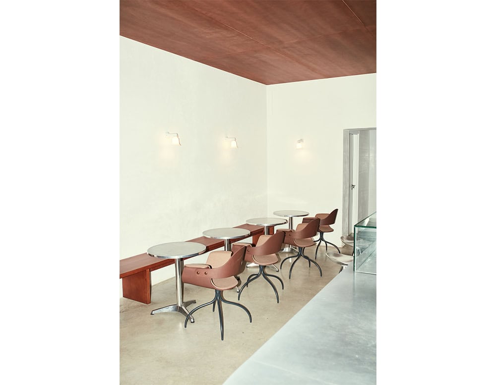 Showtime Bar Chairs featured in a soft clay-tone finish, set in a refined cafe setting. The chairs’ curved silhouettes and sculptural metal legs lend a poised yet casual presence.