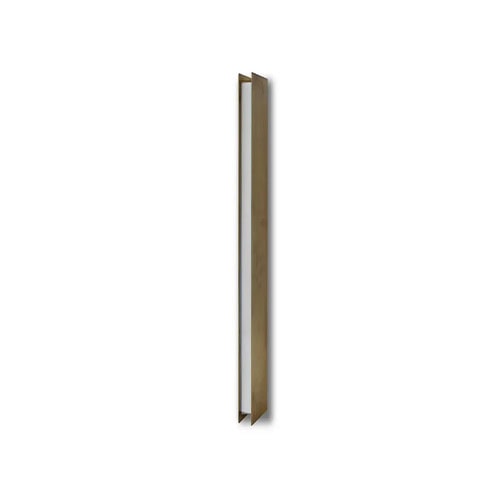 Bax Blade Wall Light features a tall narrow brass-toned frame with a recessed white diffuser that runs the length of the light. The clean white backdrop highlights its sculptural quality and linear precision.
