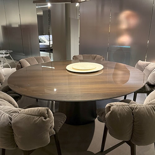 The Emmemobili UFO Dining Table is shown in a dining setup, featuring a round wood veneer top and sculptural base. It’s paired with soft, cushioned armchairs for an inviting and contemporary dining environment.