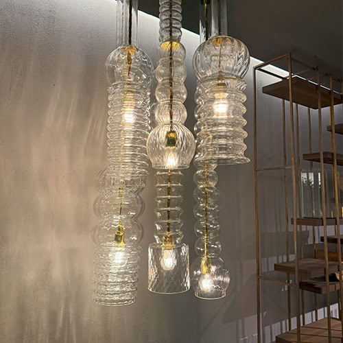 Praha Suspension Light adds visual rhythm with vertically stacked glass elements that vary in shape and texture. The ambient illumination radiates through the clear glass, enhancing architectural features and modern interiors.